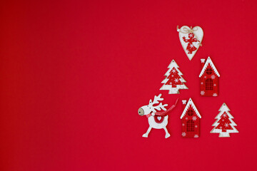 .Christmas toys on a red background. Deer, Christmas tree, house lie on the surface.