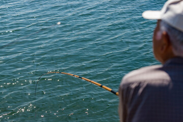 夏の海で釣りをしているシニアの男性