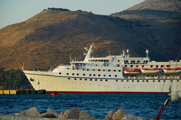 Classic cruiseship or cruise ship liner with motor yacht in port of Kefalonia in Greece during...