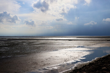 Obraz premium Waterfront at low tide with clouds - background