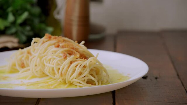Delicious Bottarga Spaghetti With Olive Oil And Fish Roe Served In A Plate On A Wooden Table - close up panning shot