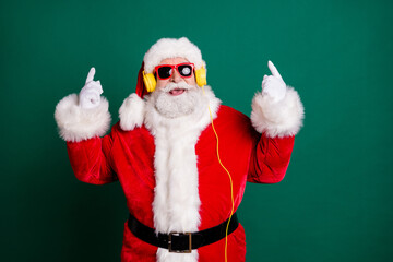 Portrait of his he nice attractive handsome cheerful cheery cool Santa listening pop music bass single melody hit having fun rhythm showing two double horn sign isolated green color background