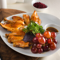 Chicken cooked in wine with grape, served on white plate in restaurant.