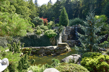 Fototapeta na wymiar Beautiful Japanese garden visited on a sunny summer day, water, rocks, waterfalls, plants, trees and landscaping.