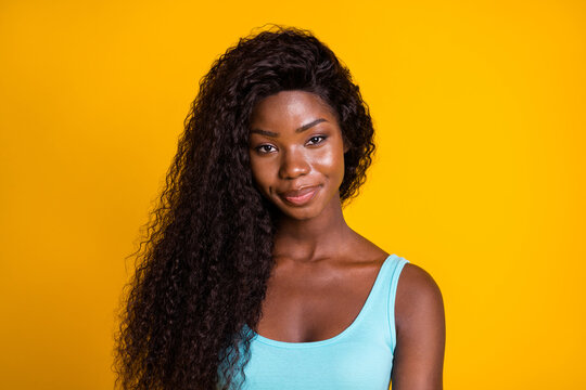 Photo portrait of smug african american woman smirking wearing blue tank-top isolated on bright yellow colored background