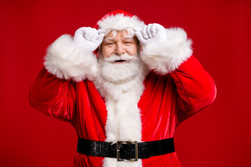 Photo of pensioner old man grey beard take off hold specs smile find taxi discount christmas eve wear santa costume belt gloves coat spectacles headwear isolated red color background