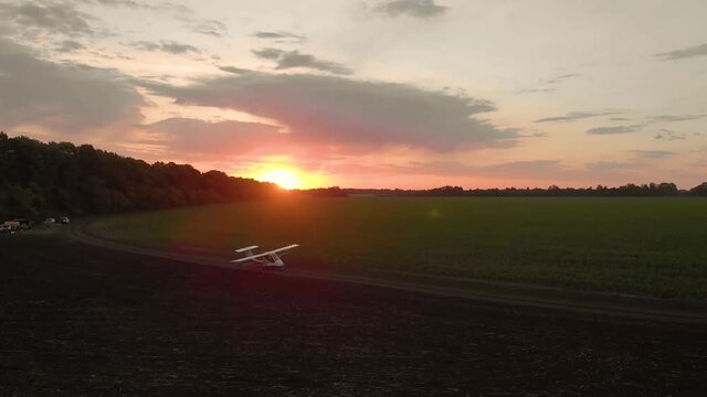 A small airplane takes off from a field.at sunrise