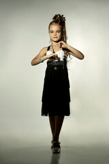 Beautiful blonde girl child in a black and white stylish dress in the studio