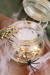 spider web and spiders in glass jar with garland on brown background