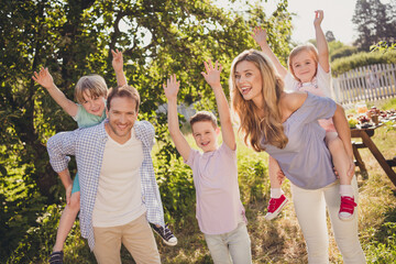 Photo full big family five people lover mommy daddy three little children gathering relax piggyback raise hand after lunch table sunny summer day home green garden backyard outside outdoors
