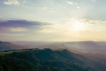 Obraz premium Early morning in the mountains. Morning sun and haze in the valley against the background of mountains. Mountain summer landscape