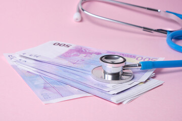stethoscope and euro banknotes on pink background, concept of the impact of the crisis on the exchange rate