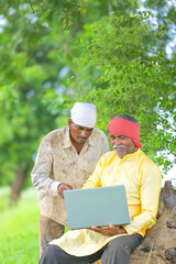 Indian farmer using laptop at field