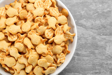 Delicious goldfish crackers in bowl on table, top view