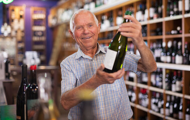 Portrait of senior man visiting winehouse in search of bottle of good wine..