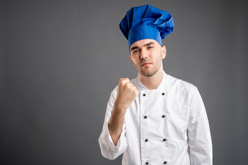 Young male dressed in a white chef suit showing fist