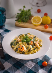 Pasta with shrimps with herbs and ingredients in a white plate on a white background