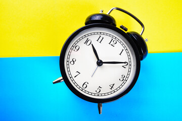 close-up black alarm clock on a yellow and blue background isolated. Lost time concept. Business idea. Lifestyle