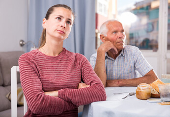 Portrait of unhappy woman sitting after quarrel with father at home interior