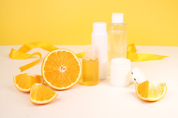Shower gel, face cream, bottle with care products with oranges on a yellow background.
