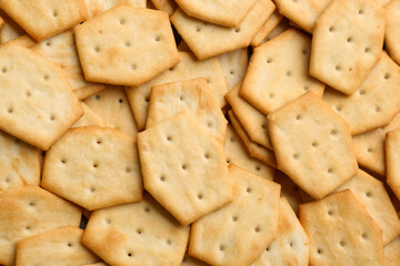 Many delicious crackers as background, top view