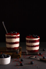 Cake in a glass. Trifles. Red velvet in a glass with berries on a dark background.