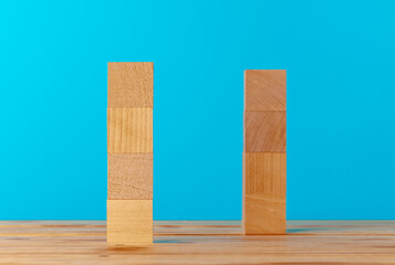 Stacked wooden blocks on wooden desk against blue background