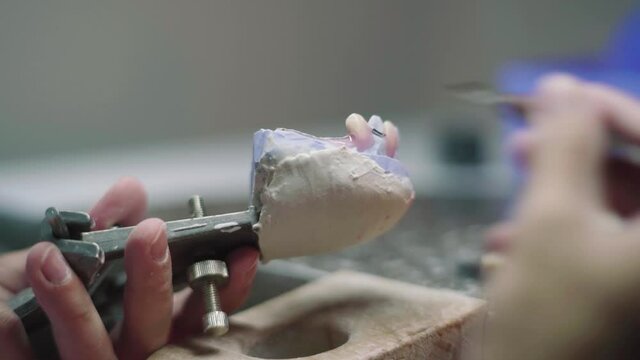 Crop male technician making dental prosthesis in lab