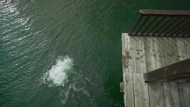 Cold Norwegian Fjord Boy Jumping Into Ocean Summer In Norway Slow Motion Shot. Boy Enjoys Swimming In Norwegian Summer In Nature. Hopping Off Diving Platform Or Tower. Green Atlantic Water