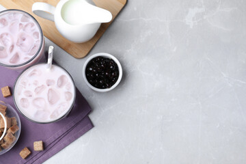 Bubble milk tea and bowl with tapioca balls on light grey marble table, flat lay. Space for text