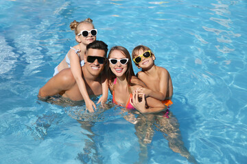 Happy family in outdoor swimming pool on sunny summer day