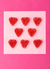 Fototapeta premium Many sugar coated pink candy hearts arranged in rows on pink background in studio setting