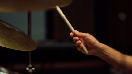 Drummer rehearsing in studio. Man hands holding drumsticks in concert hall.