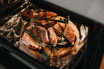 The process of baking marinated meat in a home oven. Three pieces of lard seasoned with spices and greens for roasting pork.