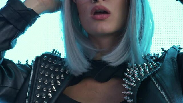 beautiful young woman posing against a led panel. teenager with alternative look posing with a colored wig