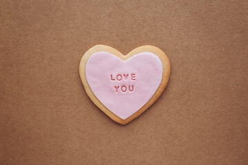 Heart shaped cookies with pink glaze and the inscription: &laquo;love you&raquo; located on a craft paper background with space for your text..Valentine's Day gifts