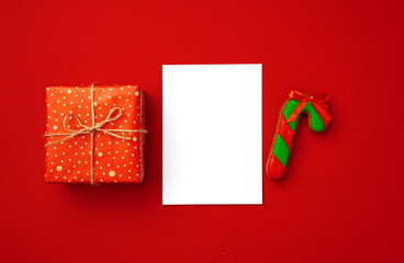Blank sheet of paper with Christmas gift and gingerbread cookies on red background
