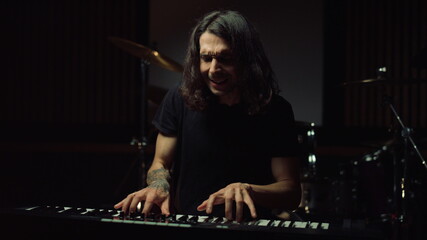 Fototapeta na wymiar Satisfied man playing in dark hall. Smiling guy rehearsing in music studio.