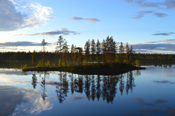 Late summers evening in Finland. Haltiajärvi, Salla. Calm water, colorful sky with cloudlets, fading light, reflection from water