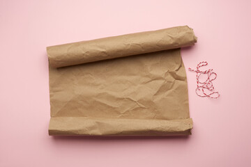 untwisted roll of brown paper on pink background, top view