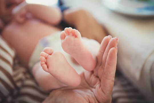 Baby feet in mother hands. Mom and her Child. Happy Family concept. Beautiful conceptual image of Maternity. The mother held the baby in her hand.