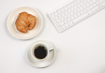 flat lay of coffee cup ,croissant ,computer keyboard on white background with copy space. Morning working time concept.