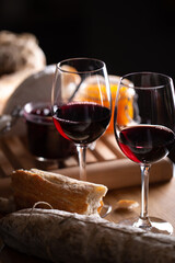 Wine glasses on table with bread and jam, dark background. Shallow depth of field, selective focus