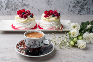 Pavlova meringue cake with cream and raspberries, blueberries, strawberries, currants. A cup of coffee, eustoma.