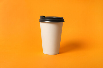 Takeaway paper coffee cup on orange background