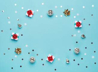 Christmas gold and silver decorations, mirror disco balls, gifts on pastel blue paper background.