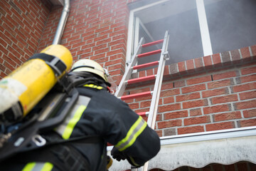 Feuerwehrmann mit Atemschutz klettert über eine Leiter in ein Gebäude