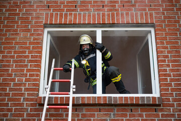 Feuerwehrmann mit Atemschutz klettert über eine Leiter in ein Gebäude