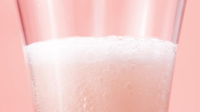 Foamy raspberry cider is poured into a glass close-up