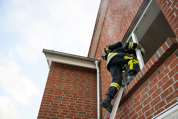 Feuerwehrmann klettert in ein Gebäude